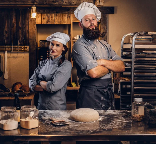 Şef asistanı aşçı üniformalı hazır hamur ekmek içinde tabloyla yakınındaki çapraz silah ile poz ile.