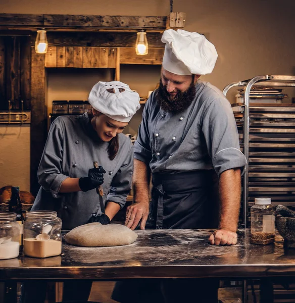 Chef teaching his assistant to bake the bread in a bakery. — Stock Photo, Image