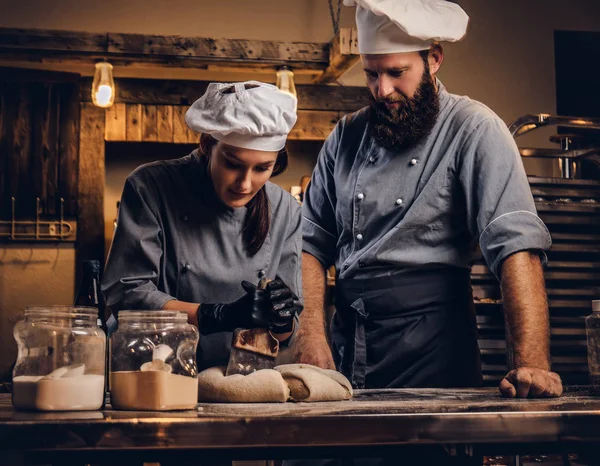 Chef-kok onderwijs zijn assistent te bakken het brood in een bakkerij. — Stockfoto