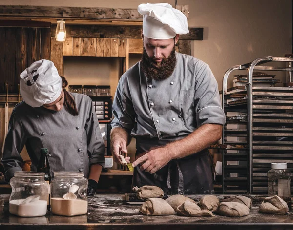 Chef teaching his assistant to bake the bread in a bakery. — Stock Photo, Image