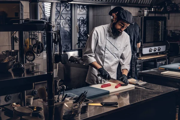 Dois cozinheiros brutais vestidos com uniformes preparando sushi em uma cozinha . — Fotografia de Stock