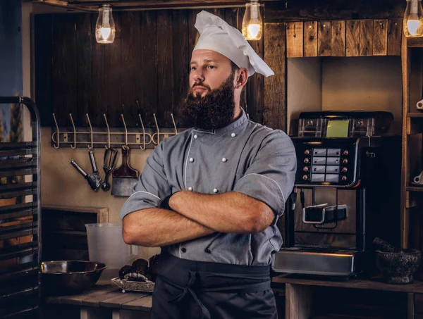 Zawodowe piekarz w mundurze kucharz pozowanie z skrzyżowanymi rękami w pobliżu w piekarni. — Zdjęcie stockowe
