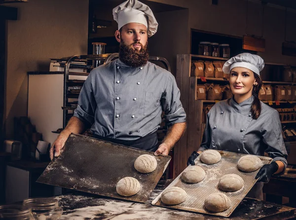 Kookles meester in de bakkerij. Chef-kok met zijn assistent klaar monsters van bakken test in keuken tonen. — Stockfoto