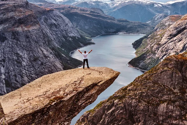 Uomo turistico in piedi nel Trolltunga e gode di una splendida vista sul fiordo norvegese . — Foto Stock