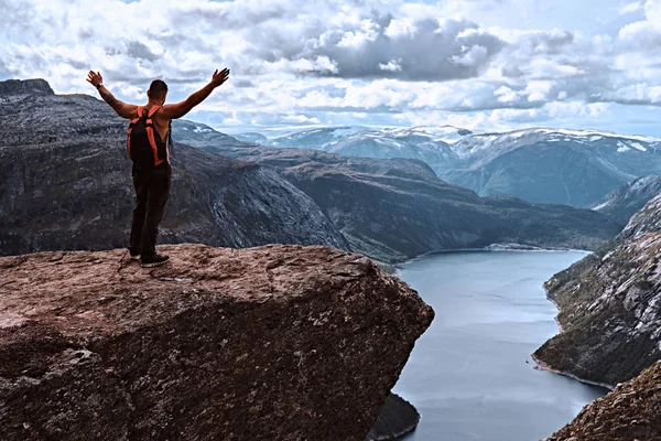 Uomo turistico in piedi nel Trolltunga e gode di una splendida vista sul fiordo norvegese . — Foto Stock