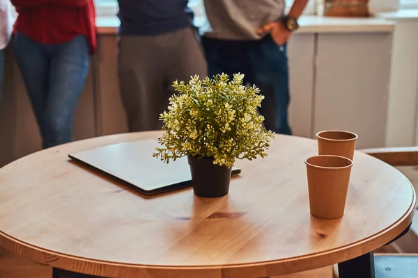 Foto in primo piano di un computer portatile, due bicchieri di carta e un fiore su un tavolo nel dormitorio degli studenti . — Foto Stock