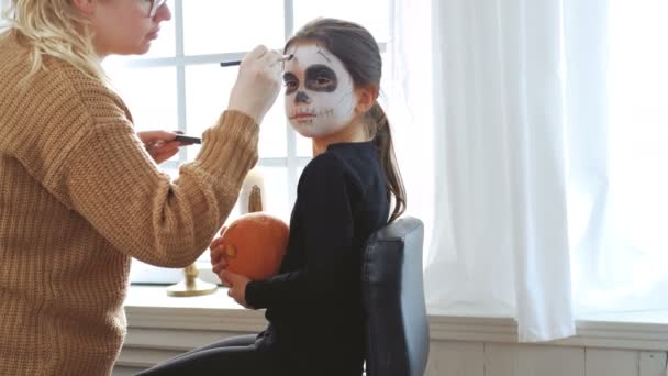 Мать рисует лицо дочери на Хэллоуин . — стоковое видео