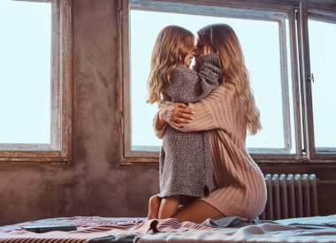 Anne ve kızı birlikte kış akşamları yatakta otururken sarılma.