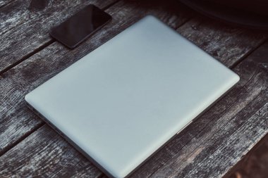 Bir dizüstü bilgisayar ve ahşap masa açık havada Smartphone'da yakın çekim fotoğraf.