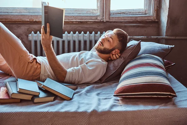 Portrét chlapa hezký studentů čtení knihy v jeho posteli. Koncepce vzdělávání. — Stock fotografie