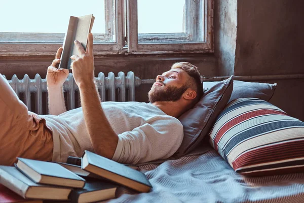 그의 침대에서 책을 읽고 잘생긴 학생 남자의 초상화. 교육 개념. — 스톡 사진