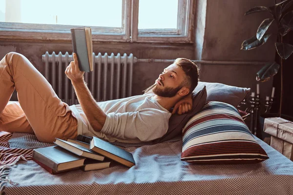 Portret przystojny student faceta z książką w jego łóżku. Koncepcja edukacji. — Zdjęcie stockowe