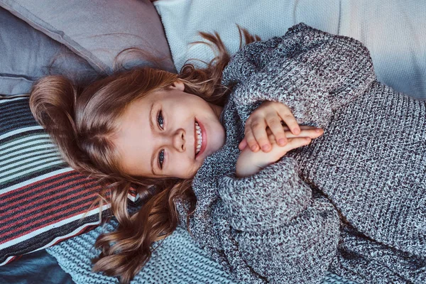 Retrato de cerca de una niña en suéter caliente acostada en la cama . — Foto de Stock