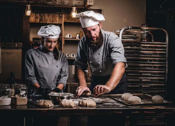 Chef ensinando seu assistente a assar o pão em uma padaria . — Fotografia de Stock