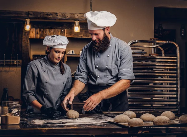 빵집에서 빵을 그의 조 수를 가르치는 요리사. — 스톡 사진