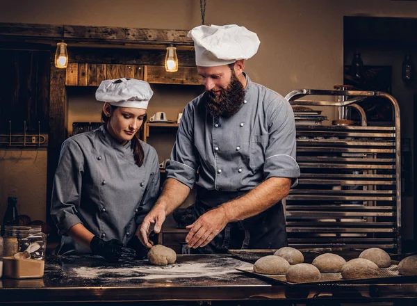 Kocken hans amanuens att baka bröd i ett bageri. — Stockfoto