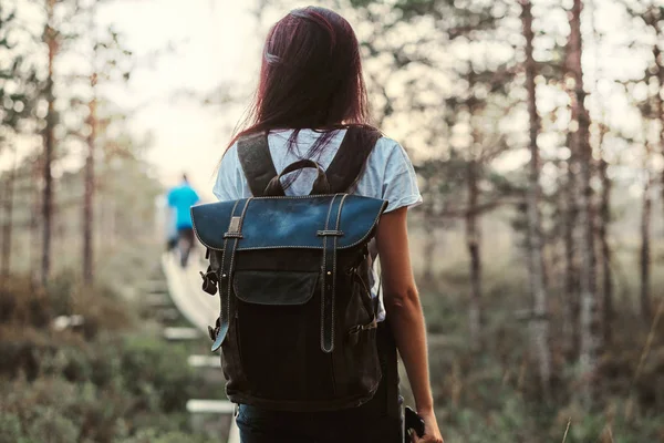 美しい森に木製歩道でバックパックの散策観光少女の背面図. — ストック写真