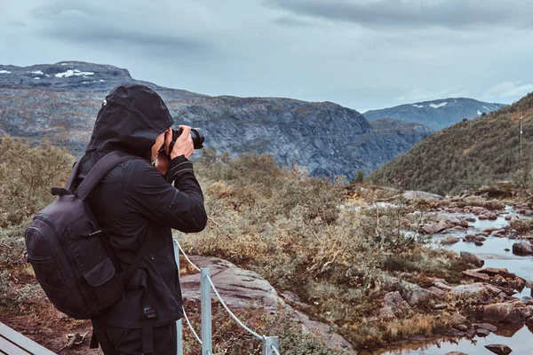 Nature photographer tourist with camera shoots while standing on the mountain. — Stock Photo, Image