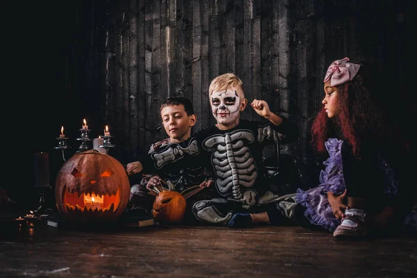 Grupo de crianças multirraciais bonitos em trajes assustadores durante a festa de Halloween em uma casa velha . — Fotografia de Stock