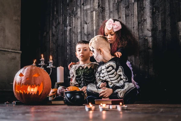 Grupo de lindos niños multirraciales en trajes de miedo durante la fiesta de Halloween en una casa vieja . — Foto de Stock