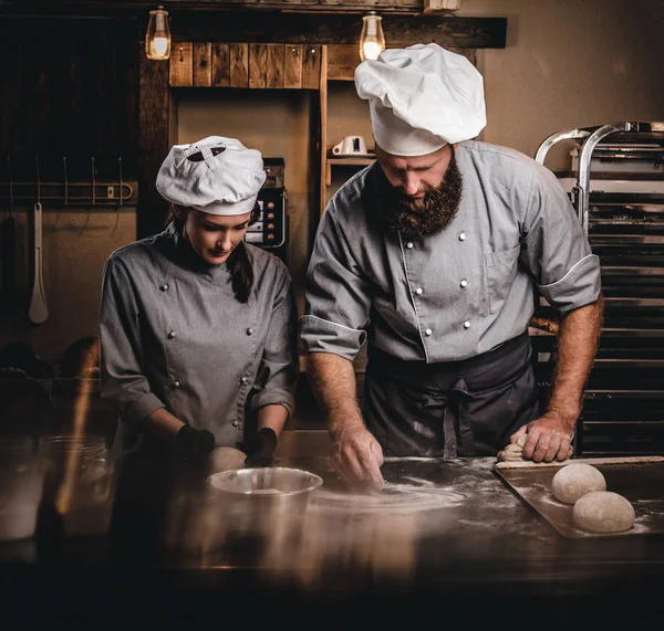 Chef ensinando seu assistente a assar o pão em uma padaria . — Fotografia de Stock