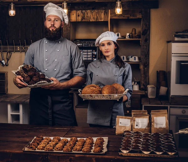 Chef with his assistant showing fresh bread in the kitchen. Promotion in bakery.