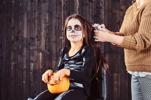 Mamma gör hår styling med en hårspray för Halloween-fest. Halloween-konceptet. — Stockfoto