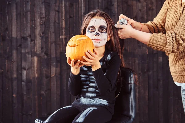 Mamma gör hår styling med en hårspray för Halloween-fest. Halloween-konceptet. — Stockfoto