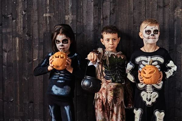 Tres niños lindos en trajes de miedo durante la fiesta de Halloween en una casa vieja . —  Fotos de Stock