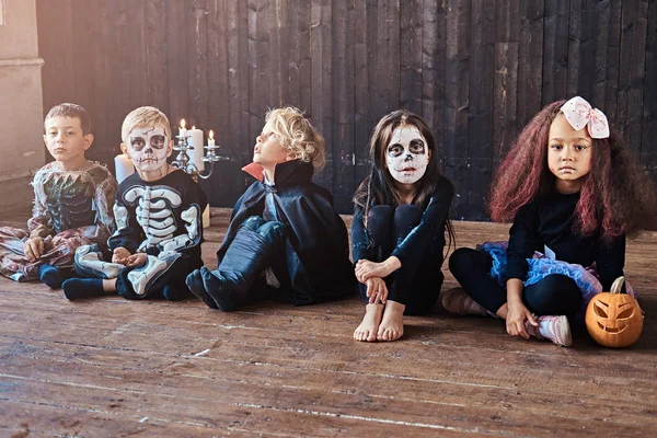 Fiesta de Halloween con niños de grupo que se sientan juntos en un piso de madera en una casa vieja. Concepto Halloween . —  Fotos de Stock