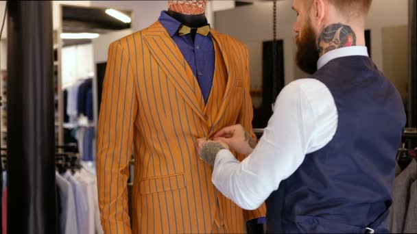Stylische tätowierte Verkäuferin knöpft sich Knöpfe an Schnuller im Herrenbekleidungsgeschäft vor. — Stockvideo