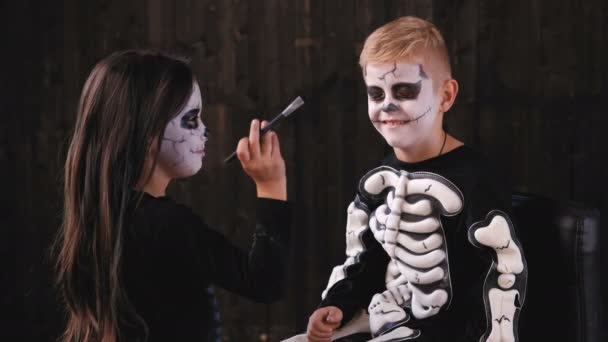 Roztomilý malý pár Připravte se na Halloween party. Dívka malba chlapce tvář ve starém domě. — Stock video