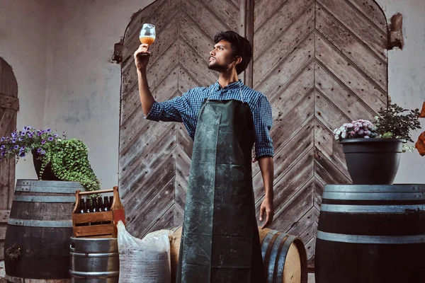 Cervecero experto en delantal de pie al aire libre comprobando la calidad de la bebida elaborada en la fábrica de cerveza . — Foto de Stock