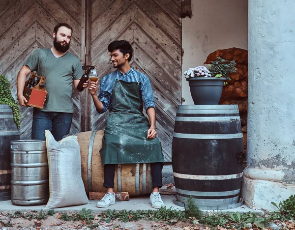 Dos cerveceros beben cerveza artesanal después del trabajo duro en la antigua fábrica de cerveza . — Foto de Stock