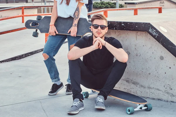 Portréja egy elegáns csípő fickó ül egy longboard: egy skatepark. — Stock Fotó