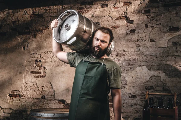 Brauer in Schürze hält Fass mit Craft Bier in Brauerei-Fabrik. — Stockfoto