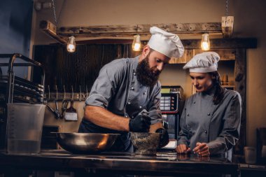 Şef susam tohumu ekmek yemek pişirmek için bir harç içinde biler. Şef Yardımcısı fırın ekmek pişirmeye öğretim.
