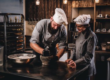 Şef susam tohumu ekmek yemek pişirmek için bir harç içinde biler. Şef Yardımcısı fırın ekmek pişirmeye öğretim.