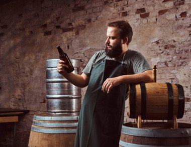 Brewer önlük ayakta yakınındaki eski bira fabrikasında varil ve içecekler zanaat bira.