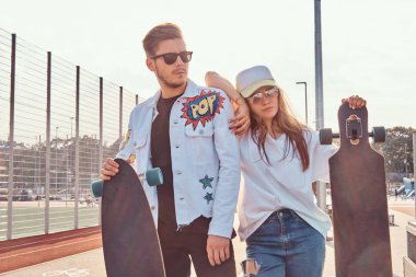 Atractive çift şık giyimli genç hipsters kaykaylar şehir spor güneşli günde kompleksi ile poz