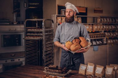 Yakışıklı sakallı Şef mutfakta Tekdüzen gösteren taze ekmek. Fırın promosyon.