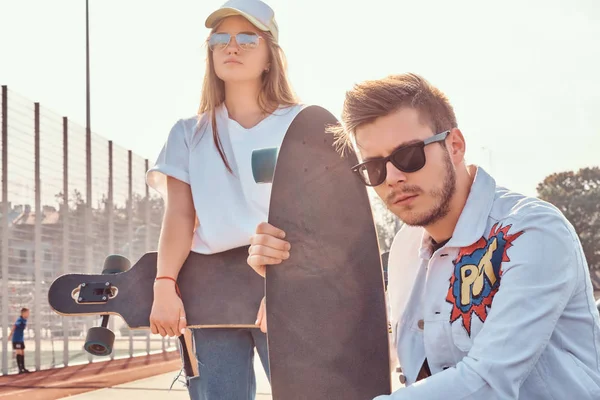 Close-up portret para młodych, modnych hipster ubrany z pozowanie w city sports complex, słoneczny dzień deskorolki — Zdjęcie stockowe