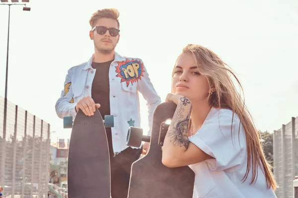 Gros plan portrait de jeune couple branché habillé hipster avec planches à roulettes posant au complexe sportif de la ville par une journée ensoleillée — Photo