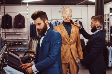 İki şık salonu zarif giymiş bir erkek giyim dükkanında çalışmaktan yardımcıları.