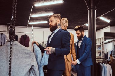 İki şık salonu zarif giymiş bir erkek giyim dükkanında çalışmaktan yardımcıları.