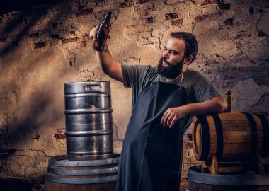 Brewer önlük ayakta yakınındaki eski bira fabrikasında varil ve içecekler zanaat bira.