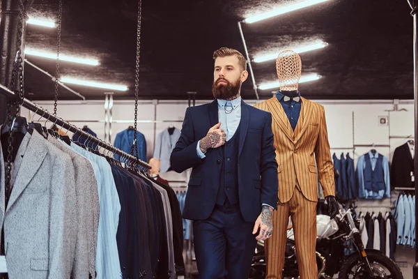 Elegant klädd skäggiga shop assistent med stående nära skyltdocka i herrkläder store. — Stockfoto