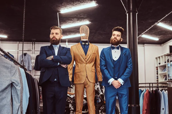 Due commesse elegantemente vestite posano vicino al manichino nel negozio di abbigliamento maschile . — Foto Stock