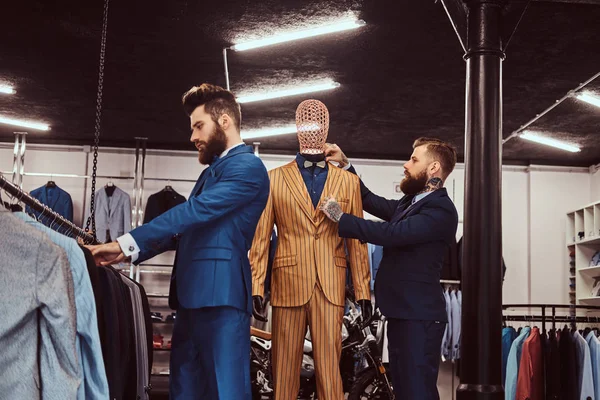 Due eleganti commesse elegantemente vestite che lavorano in un negozio di abbigliamento maschile . — Foto Stock