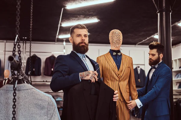 Twee stijlvolle verkoopster elegant gekleed werken in een winkel herenkleding. — Stockfoto